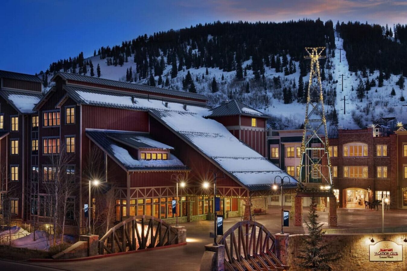 Ein Hotel mit Skilift, schneebedeckten Dächern und einer Bergkulisse.