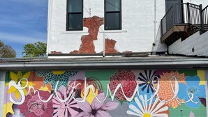 Un bâtiment orné d’une fresque murale colorée sur le côté, avec de grands motifs floraux et le texte « Smithville ».