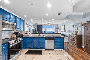 A kitchen with blue cabinets, stainless steel appliances, and a wooden floor.