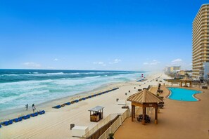 A beachside hotel with a pool, beach chairs, and a lifeguard stand. - Beachfront escape w/ free daily attractions and pool (Panama City Beach)