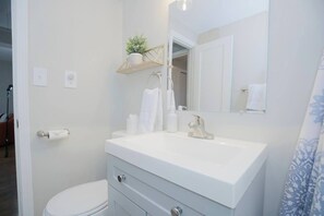 Een badkamer met een wit wastafel, een spiegel, een handdoekhouder en een toilet.