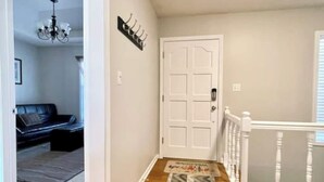 A hallway with a wooden floor, a patterned rug, a white door, and a staircase with white railings. - The Bird House has at least one ‘bird’ in each room. How many can you find? (Kansas City)