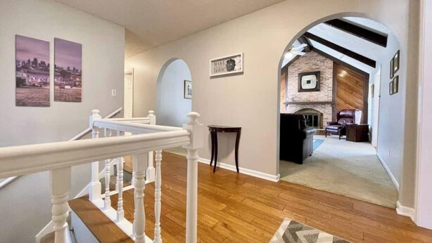 A spacious living area with a wooden floor, a staircase with white balusters, and a fireplace with a brick wall. - The Bird House has at least one ‘bird’ in each room. How many can you find? (Kansas City)