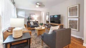 Ein modernes Wohnzimmer mit einer Couch, einem Couchtisch, einem Fernseher und Kunstwerken an den Wänden.