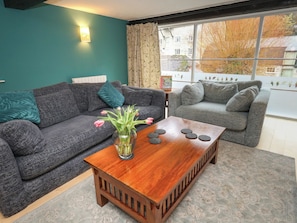A living room with two grey sofas, a wooden coffee table, and a vase with flowers. - The Grain Store (Weymouth)