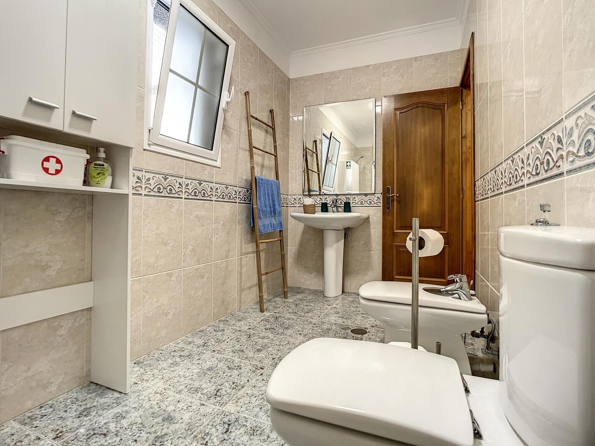 A bathroom with a toilet, sink, and window.