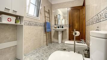 A bathroom with a toilet, sink, and window.