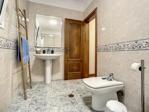 Une salle de bain avec une porte en bois, un lavabo, un bidet et un miroir.