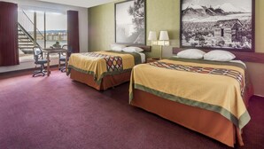 A hotel room with two beds, a desk, chairs, a staircase, and large framed pictures on the walls. - Super 8 by Wyndham Wells (Wells)