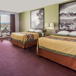 Une chambre d’hôtel avec deux lits, un bureau et une vue sur l’extérieur.