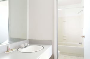 Un baño con un lavamanos blanco, un espejo y una zona de ducha.