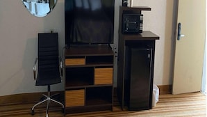 A hotel room with a flat-screen TV, a microwave, a small refrigerator, a wooden entertainment unit, and a door with a number sign. - Super 8 by Wyndham Wells (Wells)
