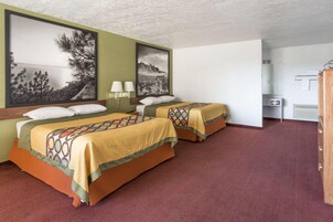 A hotel room with two beds, a large painting on the wall, a desk, and a wardrobe.