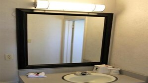 A bathroom with a large mirror, a sink, and a towel dispenser. - Super 8 by Wyndham Wells (Wells)