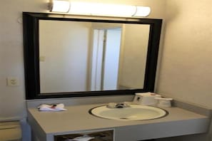Une salle de bain avec un grand miroir, un lavabo et un distributeur de serviettes.