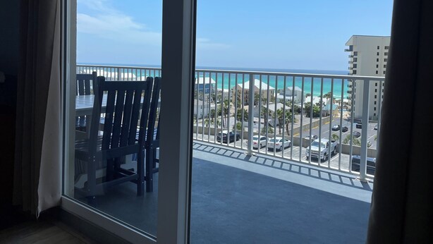 Un balcon avec vue sur l’océan et un espace de stationnement.