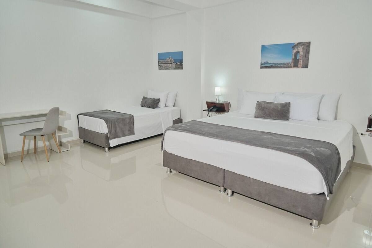 A hotel room with two beds, a desk, and a chair.
