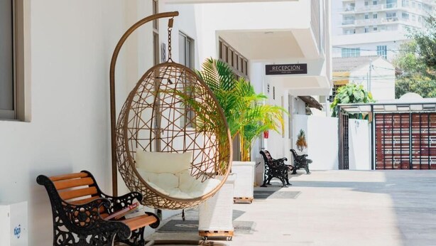 A reception area with a hanging chair, a bench, and a black metal bench. - Hotel El Marques de Manga (Cartagena)