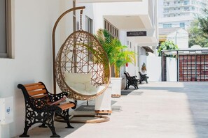 A reception area with a hanging chair, a bench, and a black metal bench. - Hotel El Marques de Manga (Cartagena)