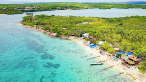 An aerial view of a coastal area with a beach, clear turquoise waters, and lush greenery. - Hotel El Marques de Manga (Cartagena)