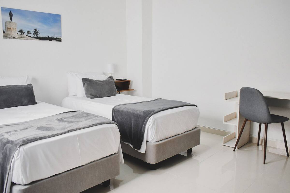 A hotel room with two beds, a desk, and a chair.