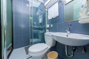 Un baño moderno con ducha envuelta en vidrio, inodoro blanco y lavamanos con espejo.