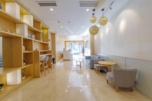 A modern interior with wooden shelving, a reception desk, seating area, and a view to the outside. - Hi Inn (Shanghai Hongqiao Railway Station) (Shanghai)