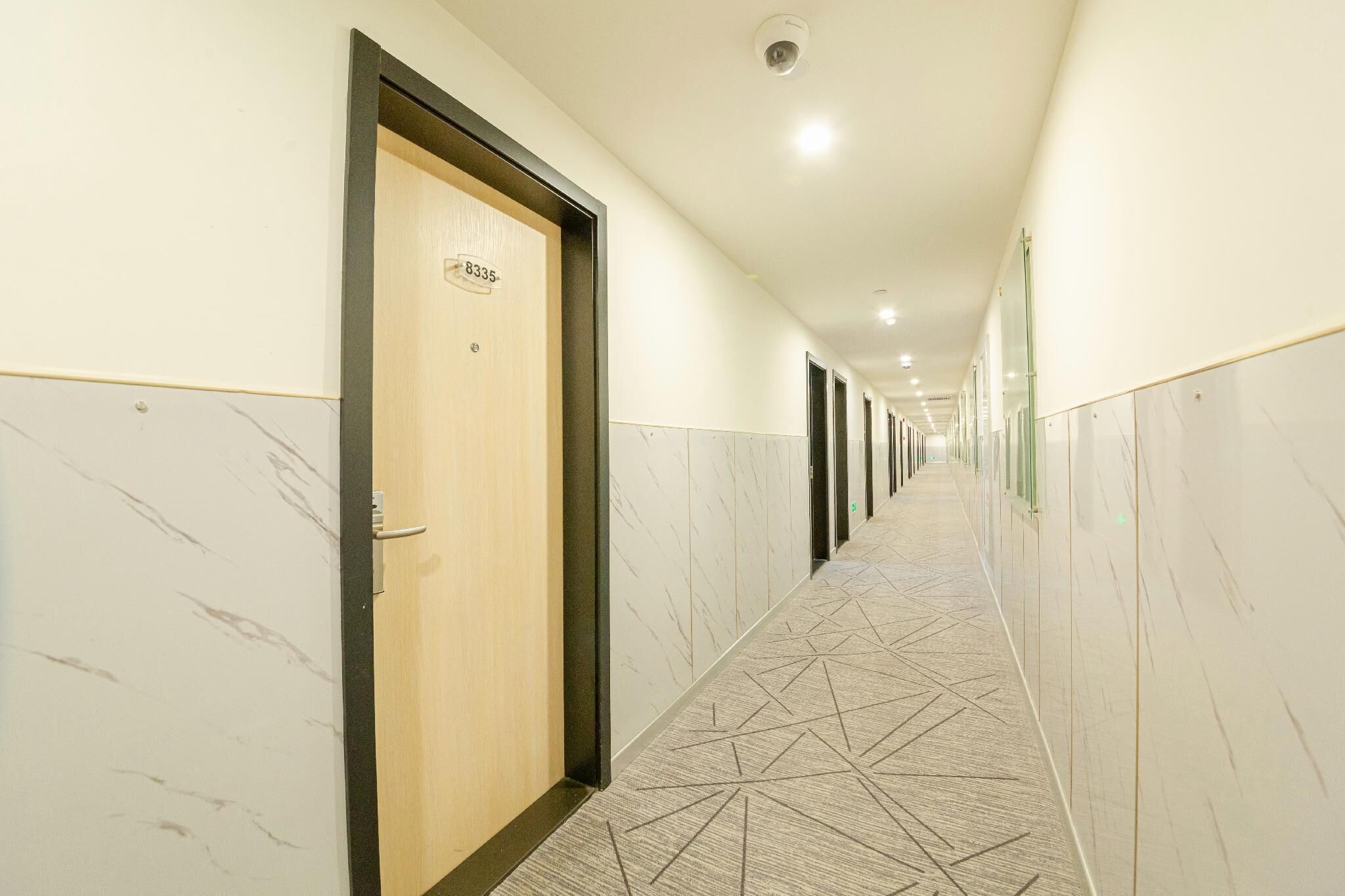 A long, well-lit hallway with marble walls and a geometric carpet pattern.