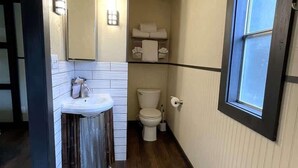 A compact bathroom with a toilet, sink, and mirror. - Mountain Zen (Alto)