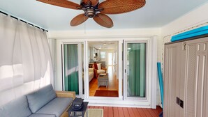 A room with a ceiling fan, a sofa, a coffee table, and a view through sliding glass doors to a dining area.