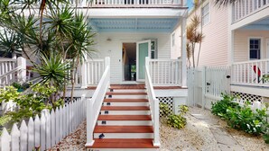 A staircase leading to a porch with a white picket fence and a door.