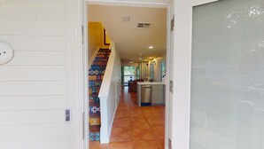 A hallway with a tiled staircase leading to a balcony.