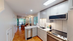 A modern kitchen with white cabinets, a built-in microwave, and a stainless steel stove.