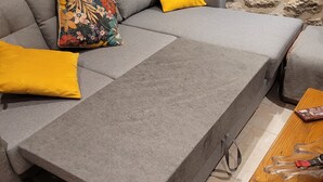 A grey sofa with yellow cushions, a wooden table, and a lamp. - Forsythias (Messeix)