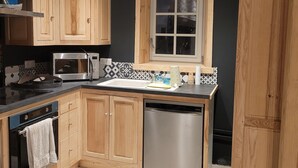 A modern kitchen with wooden cabinets, a stainless steel dishwasher, and a microwave. - Forsythias (Messeix)