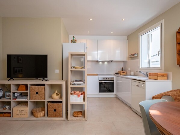 A modern kitchen with white cabinets, a built-in oven, and a window.