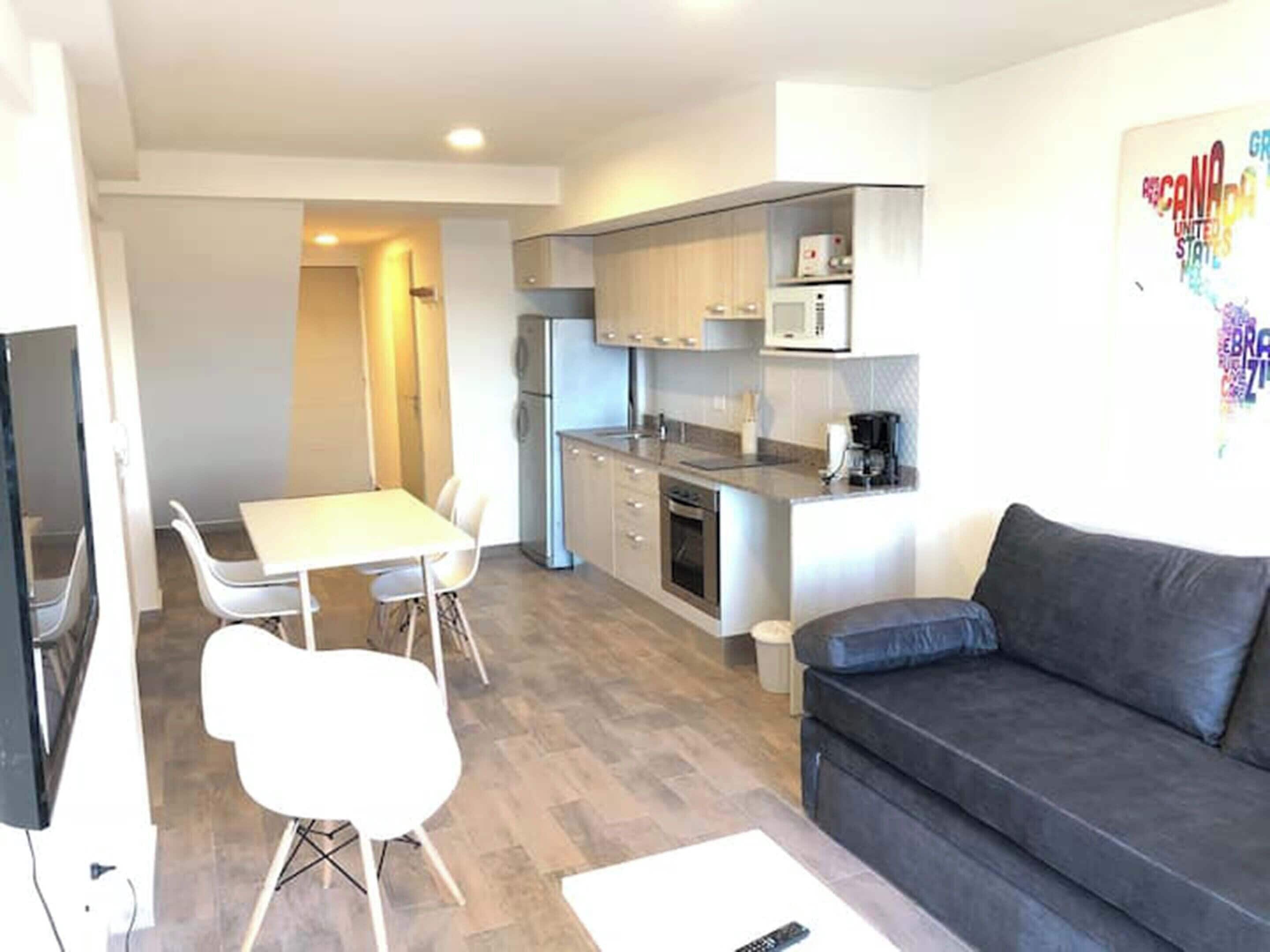 Un espacio habitable compacto con kitchenette, comedor y sofá.