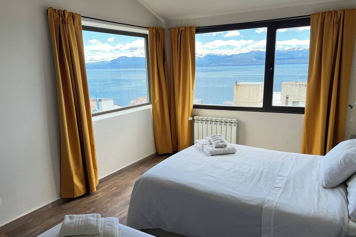 Habitació d'hotel amb dos llits, vista al mar i a les muntanyes, i un radiador.