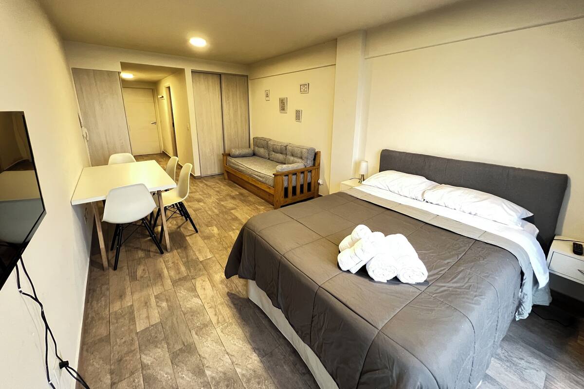 Habitació d'hotel amb llit, sofà, escriptori i cadires, i televisió.