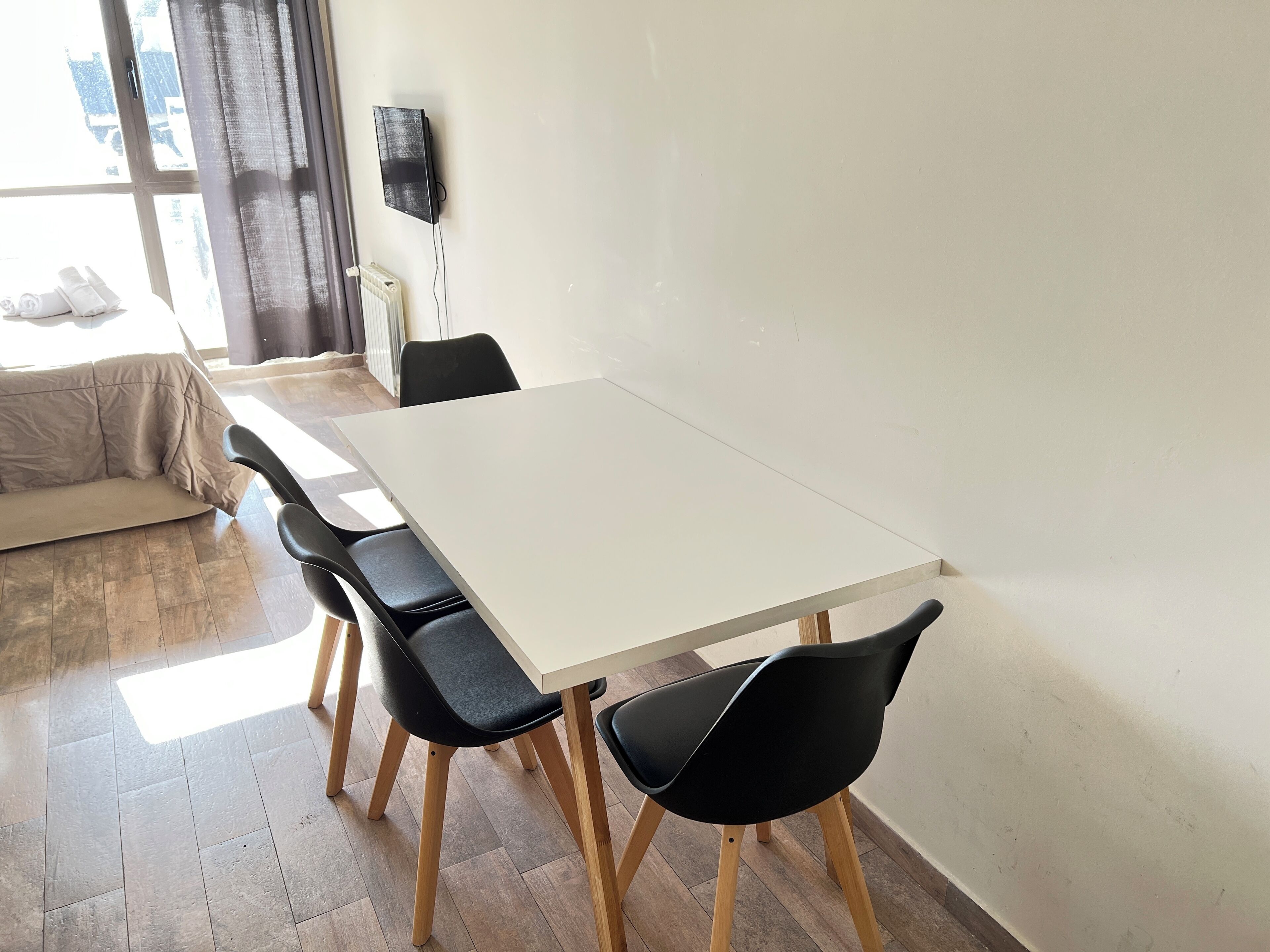 Een moderne eethoek met een witte tafel en zwarte stoelen, een bank en een radiator.