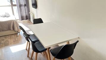 Een moderne eethoek met een witte tafel en zwarte stoelen, een bank en een radiator.