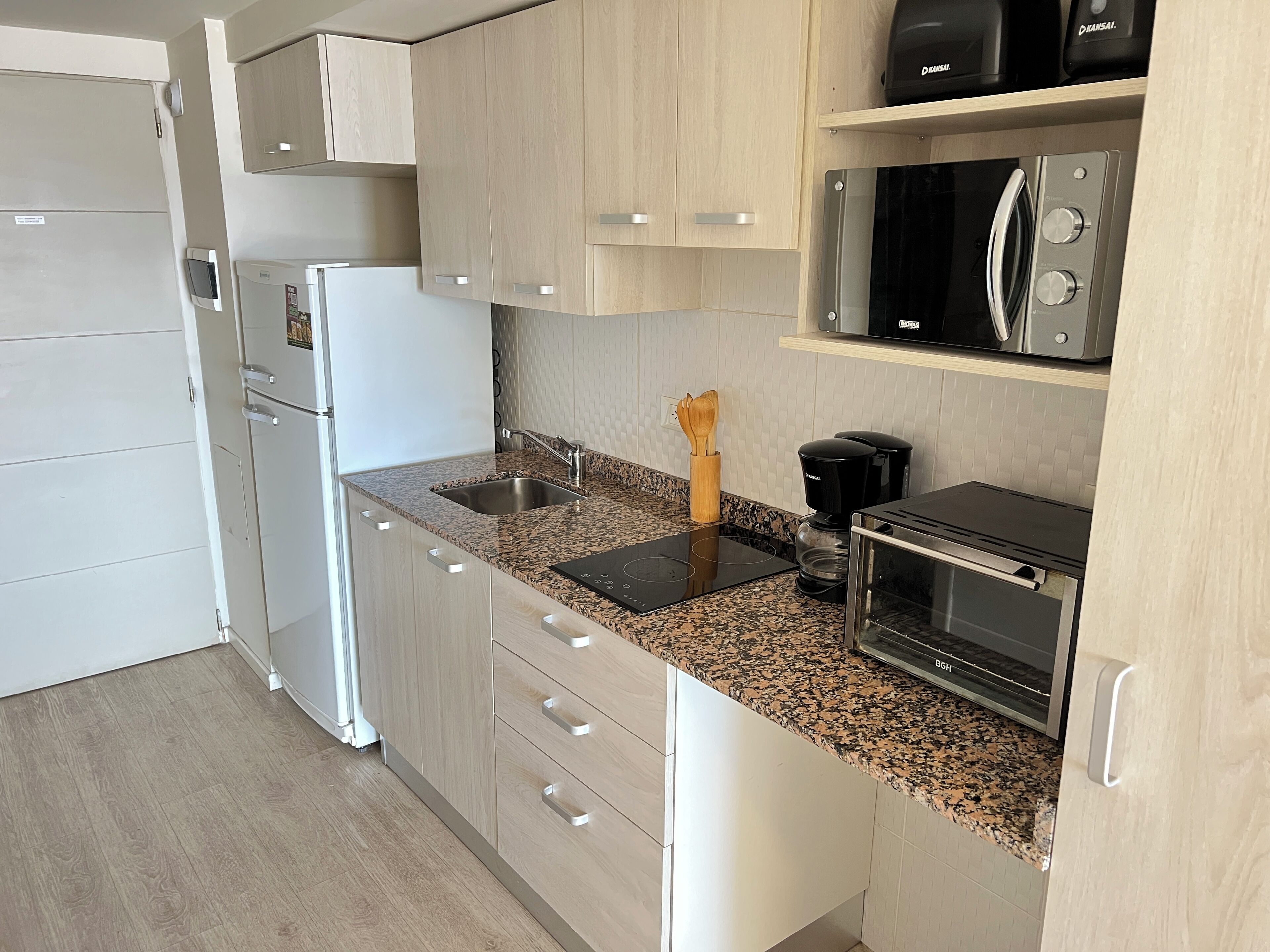 A modern kitchen with a built-in microwave, coffee maker, and a toaster.