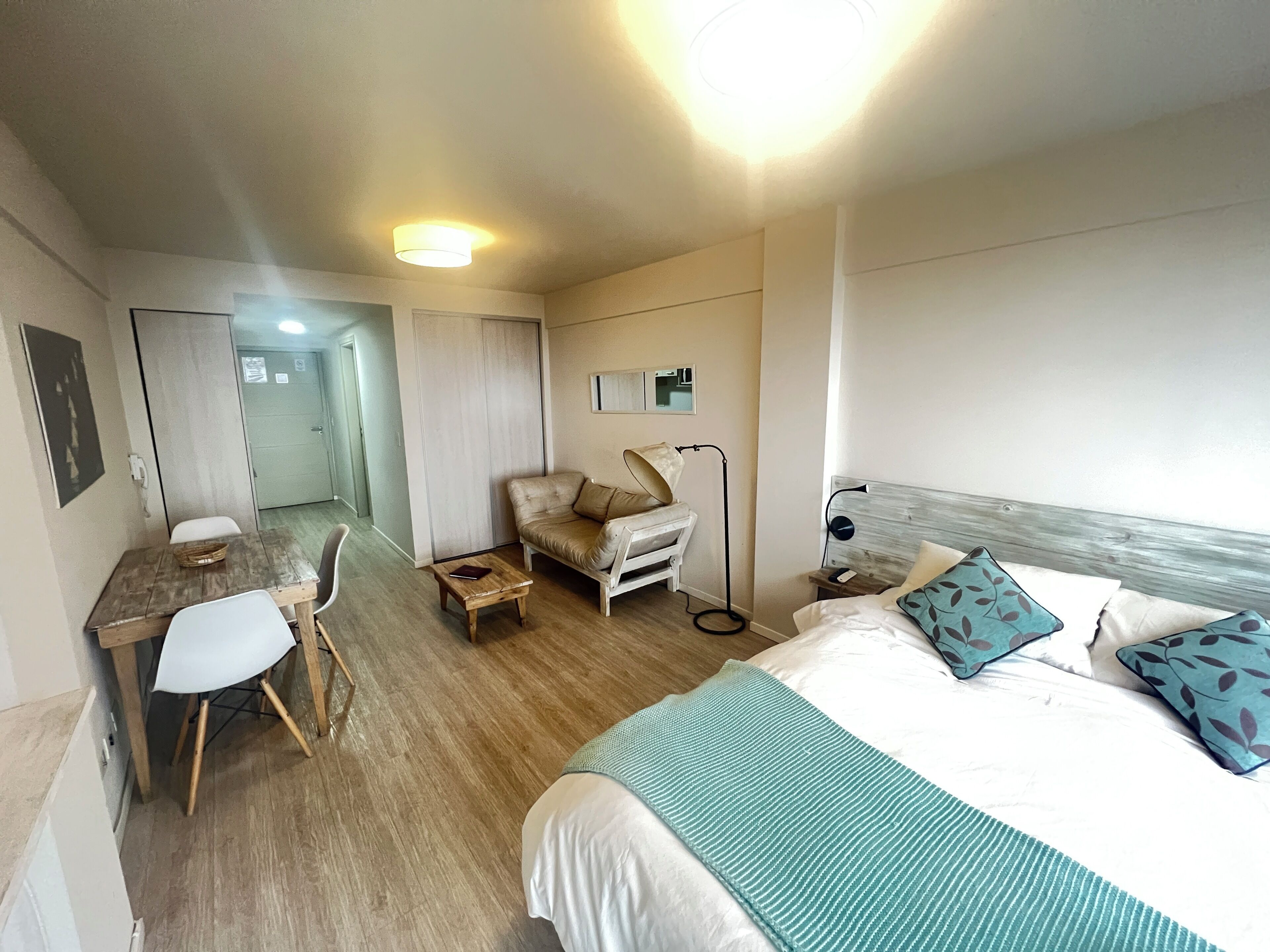 Una habitación de hotel con cama, escritorio, silla, sofá y mesita de noche.