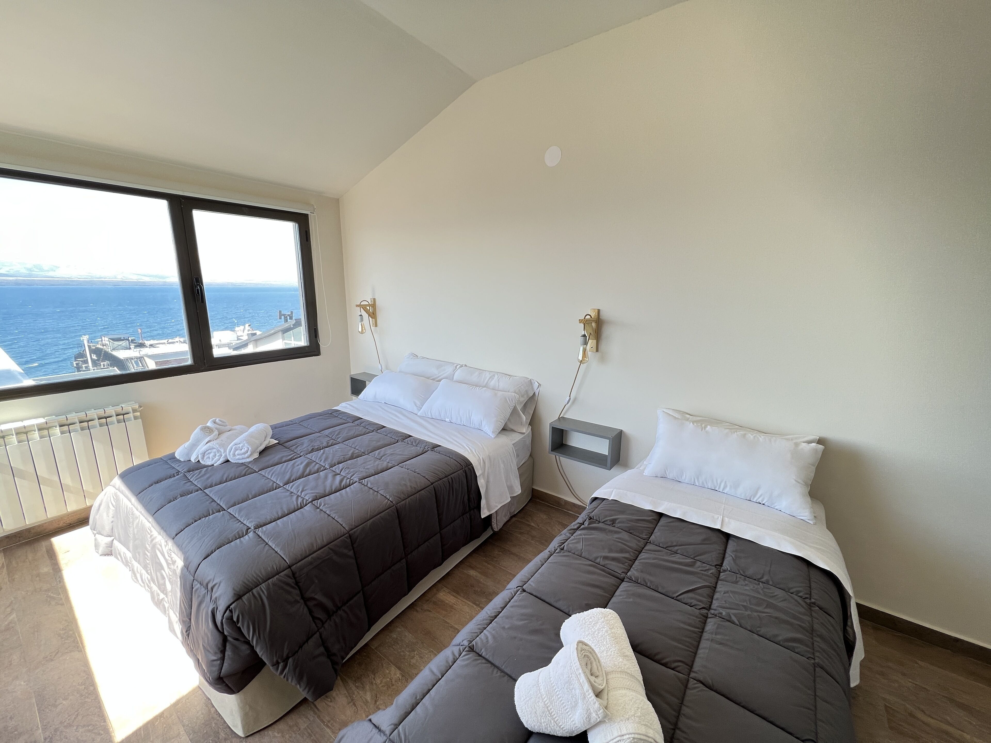 A bedroom with two beds, a view of the sea, and a window.