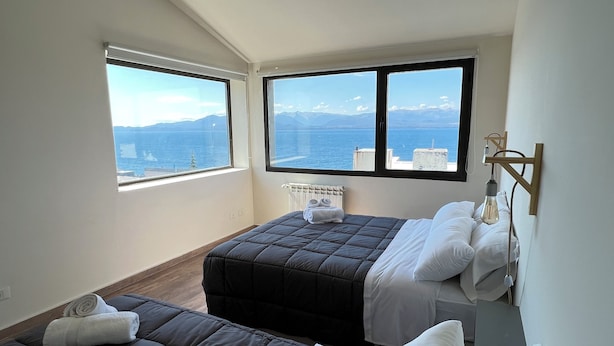 Une chambre avec deux lits, un radiateur et vue sur la mer.