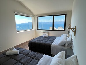 Un dormitorio con dos camas, un radiador y vista al mar.