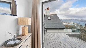 A modern room with a large window, a wooden desk, a lamp, and a vase with flowers. - The Sail Loft Suite - Sea View - Private patio (Brixham)