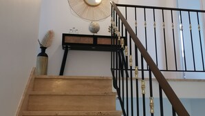 En trappa i trä med svarta räcken och detaljer i mässing, som leder upp till en liten plattform med en dekorativ spegel och en jordglob.