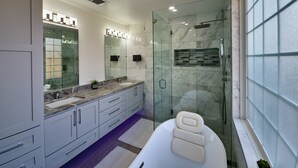 Ein modernes Badezimmer mit Duschkabine aus Glas, einem großen Spiegel und einer weißen Badewanne.