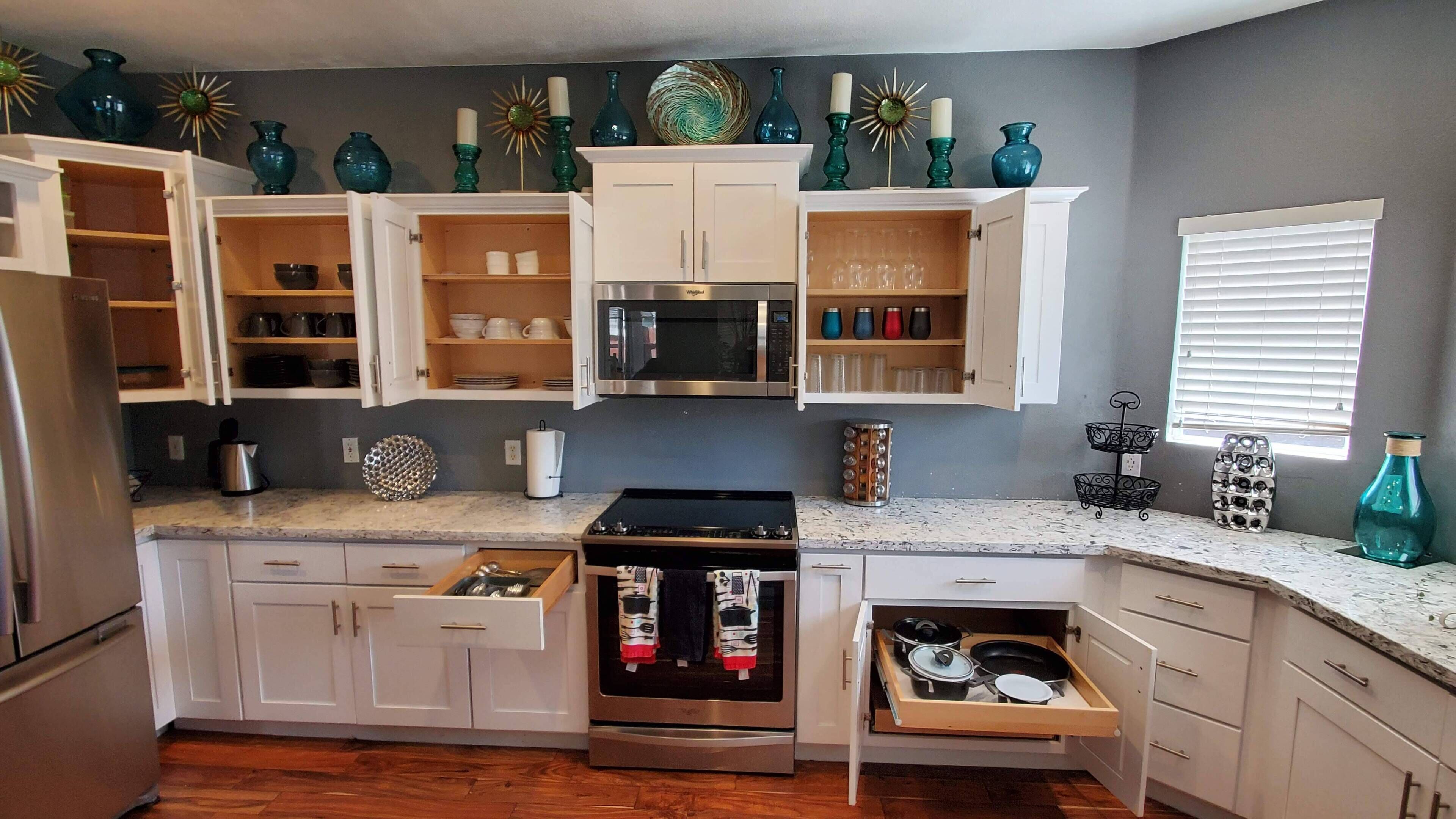 A kitchen with white cabinets, a microwave, a stove, and various decorative items on the shelves.